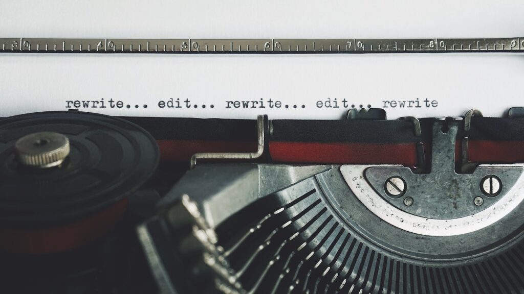 JLNICH blog beats article, The NaNoWriMo Diaries: Overcoming Self-Doubt and Perfectionism. image for relentless self-criticism. Type writer with the words rewrite... edit... rewrite... edit