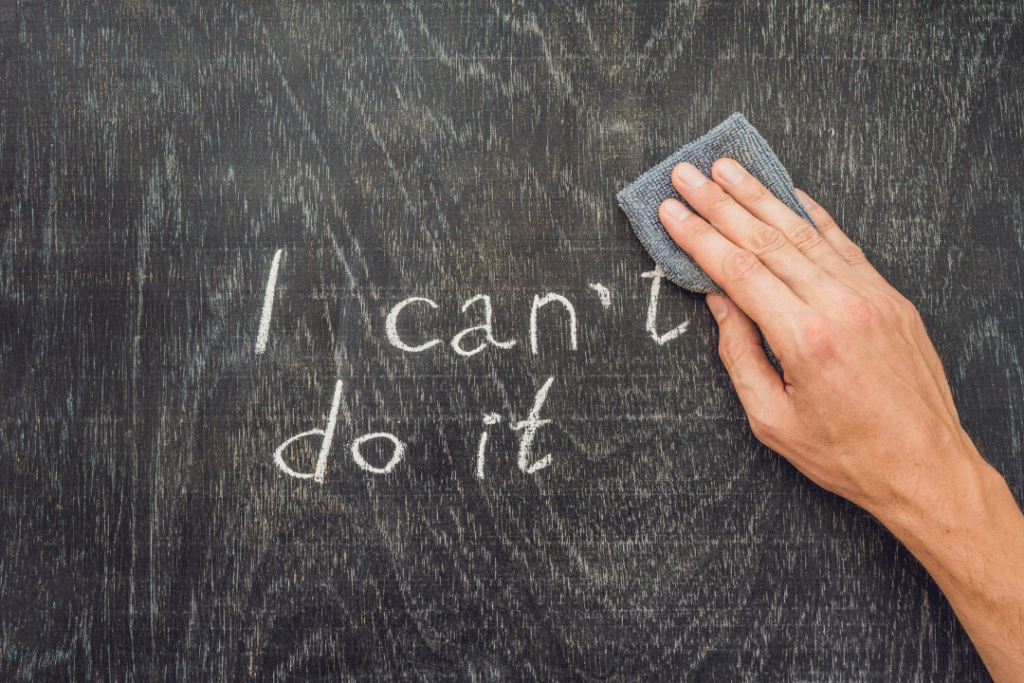 JLNICH blog beats article, The NaNoWriMo Diaries: Overcoming Self-Doubt and Perfectionism. image for negative self-talk. Image of I can't do it being erased by a hand