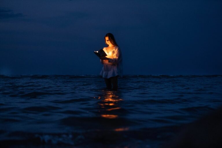 JLNICH blog beats article, The ABCs of Awesomeness: Adding Brilliance to Your Manuscripts. Cover image, lady standing in water reading a book that is shining light